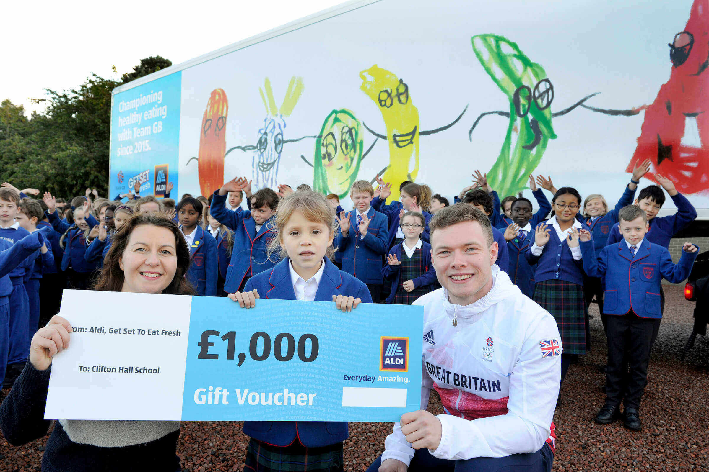 Team GB's Jack Carlin with Design a Lorry winner, Isabella, her teacher, Rhona Robertson and classmates in front of her lorry!